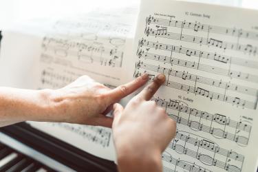 2 fingers pointing at sheet music on a piano