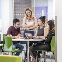 Four business students sitting around a table discussing their work