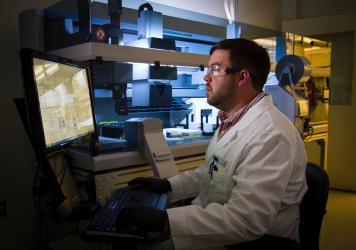 A man in lab sitting in fromt of a computer.