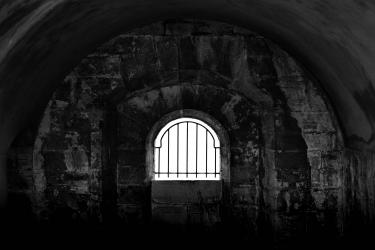 Dark prison cell with barred window