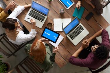 looking downwards at people sitting around a table with their laptops