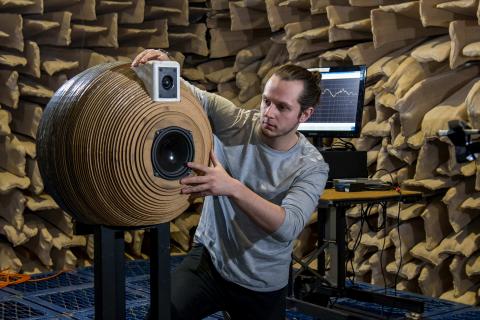 A student positioning a novel, spherically-designed speaker system inside the large anechoic chamber for testing.