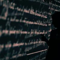 Stock image of a researcher's silhouette set against a wall projection of written language.