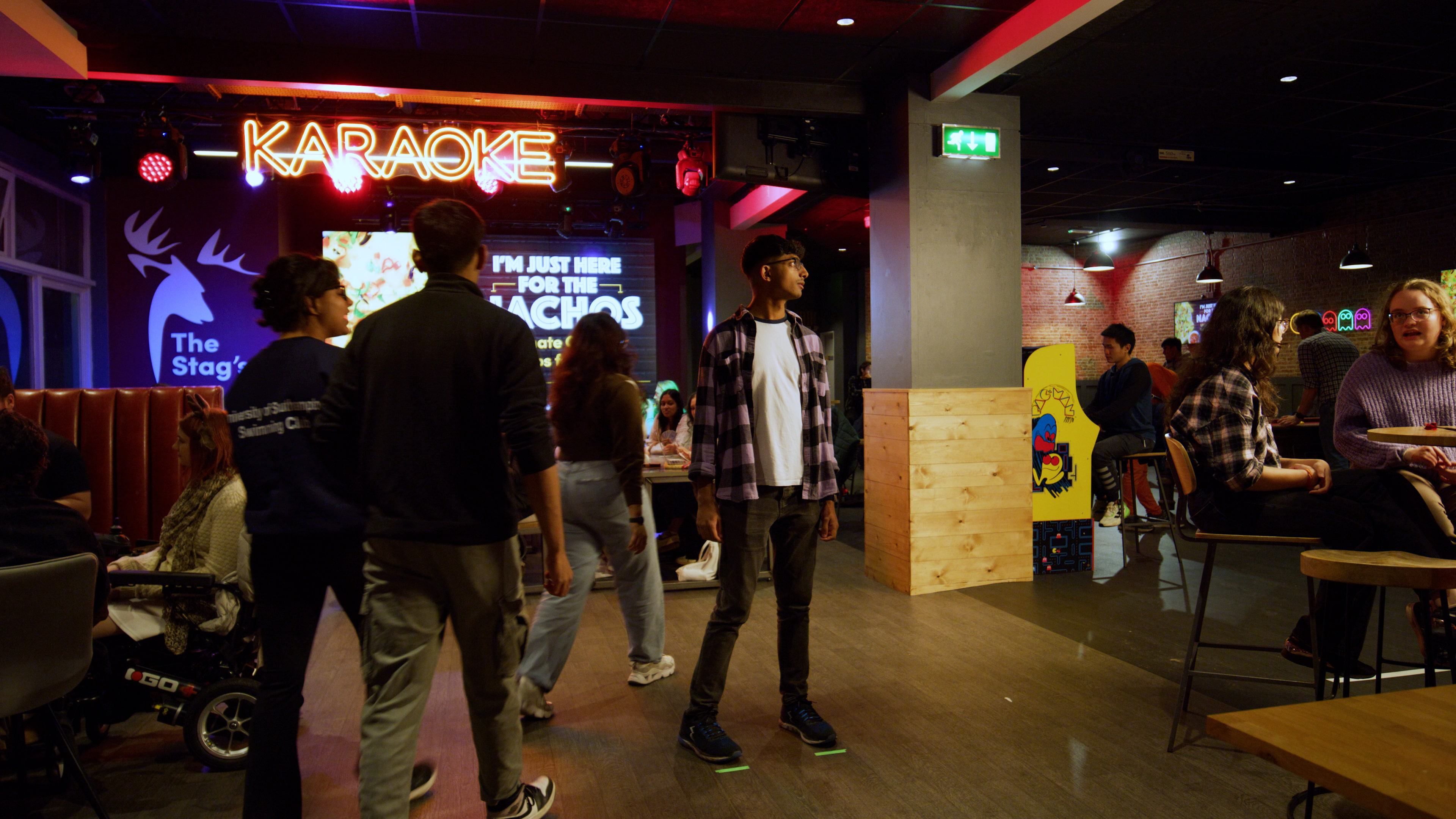 A student stood beneath a neon karaoke sign in a busy students' union bar.