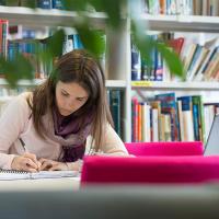 Student writing at desk