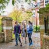 Students walking through gates outside the impressive buildings of Avenue Campus.