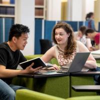 Two students collaborate on project work in a quiet learning space