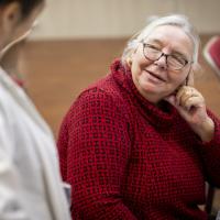 woman wearing a red jumper listening to another woman.