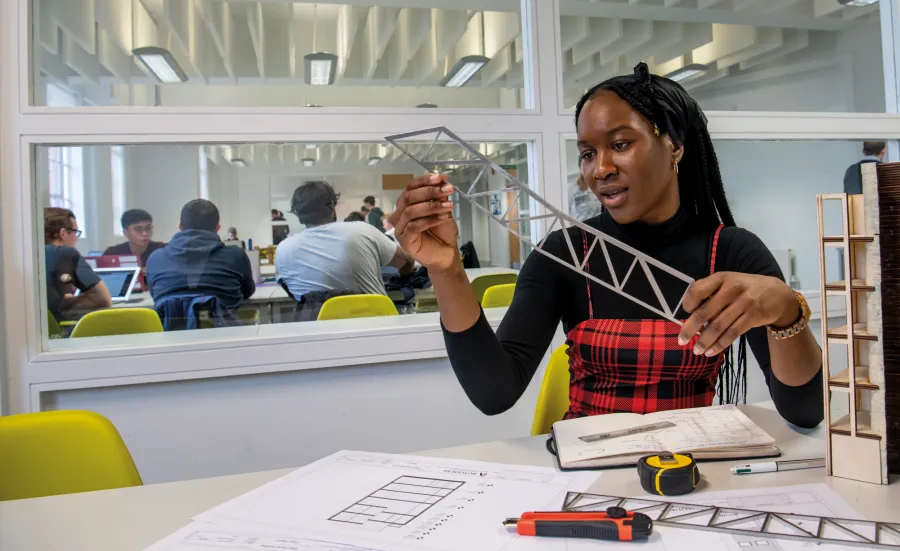 Civil engineering student Virtue Igbokwuwe, a young Black woman, works on a design at a desk in our campus building, immersed in her work